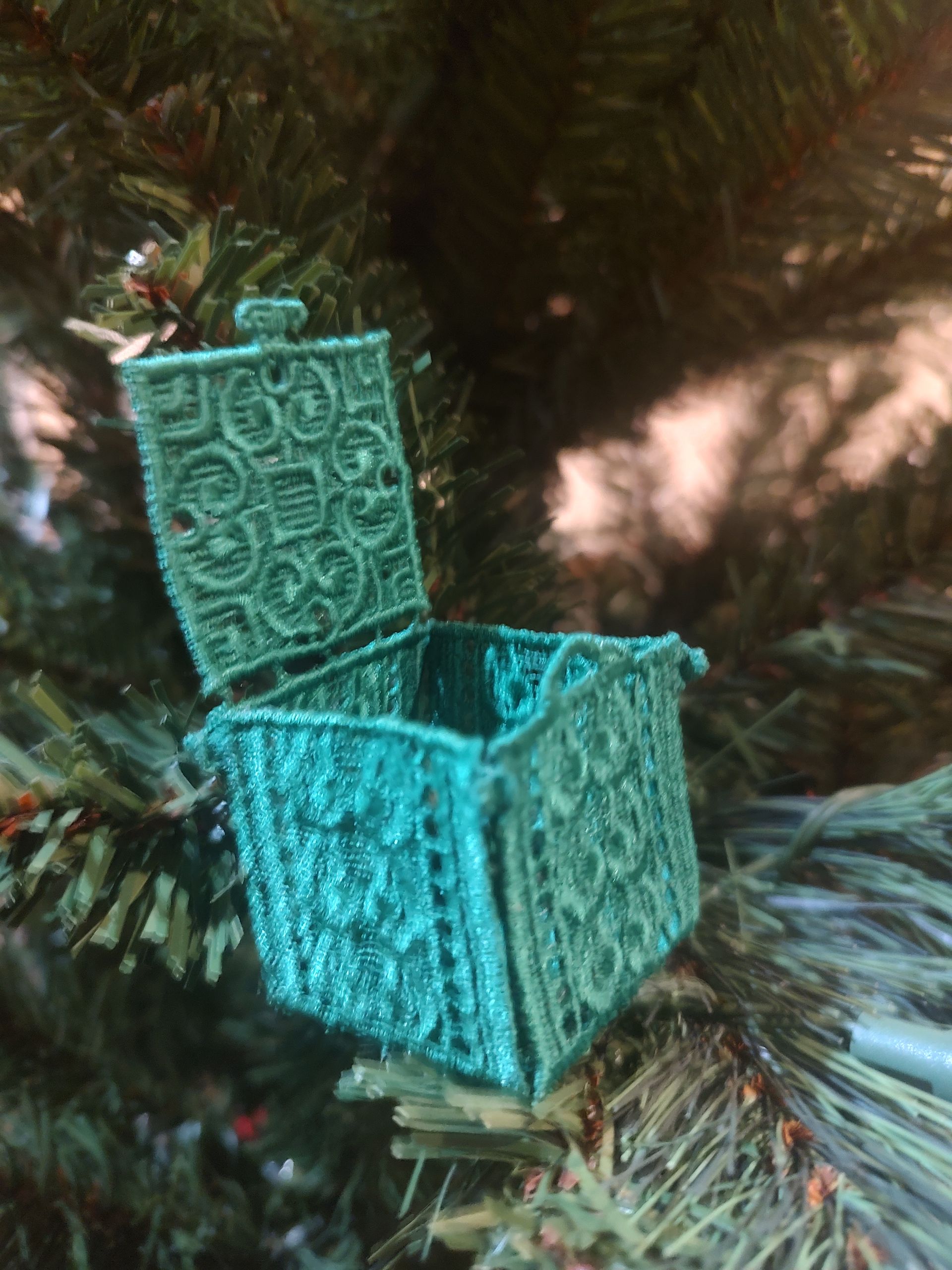 Green, ornate, open, miniature chest ornament on Christmas tree.
