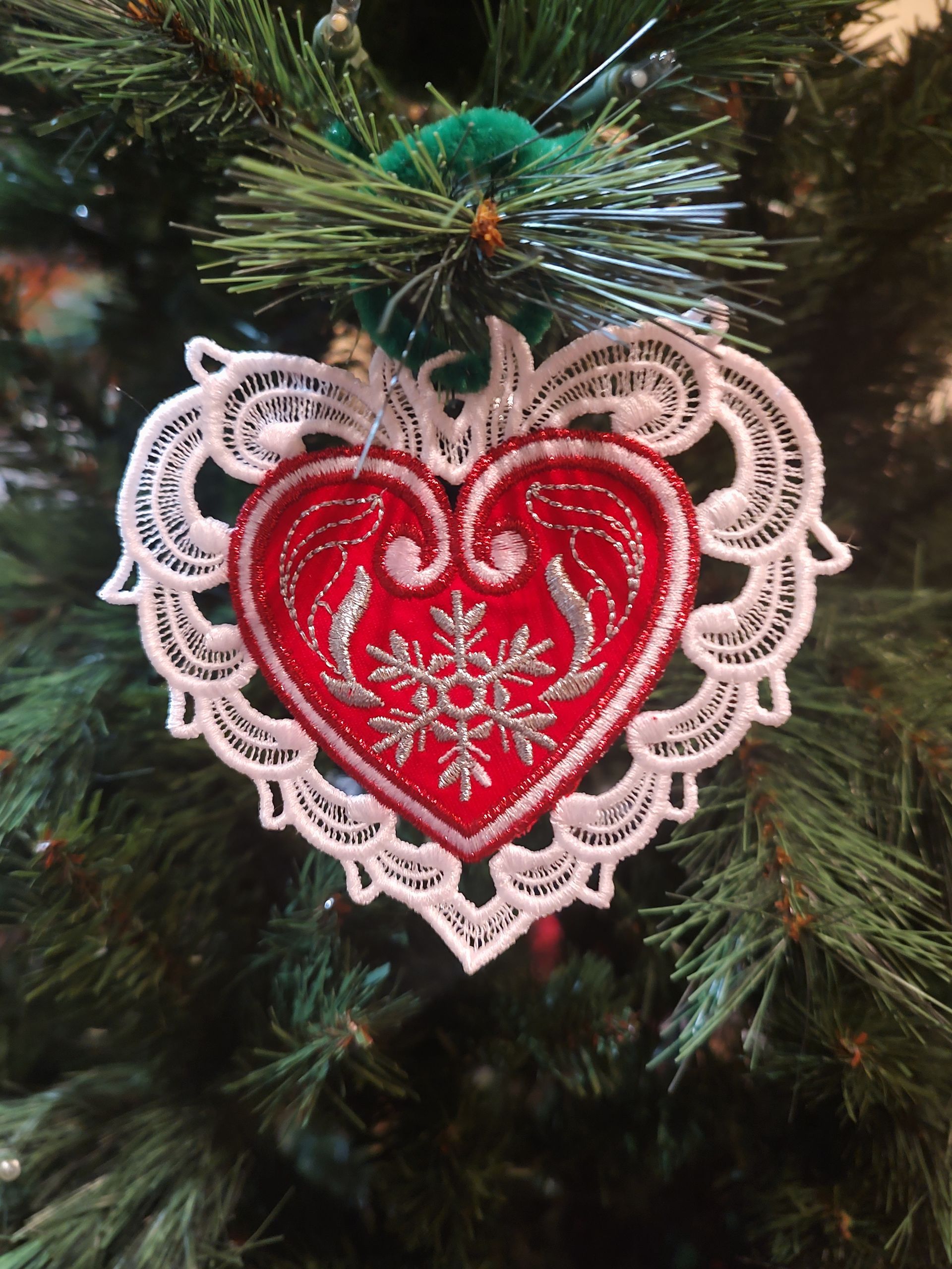 Stunning heart-shaped applique framed by a delicate thread-only lace design. A metallic silver snowflake elegantly anchors the composition.