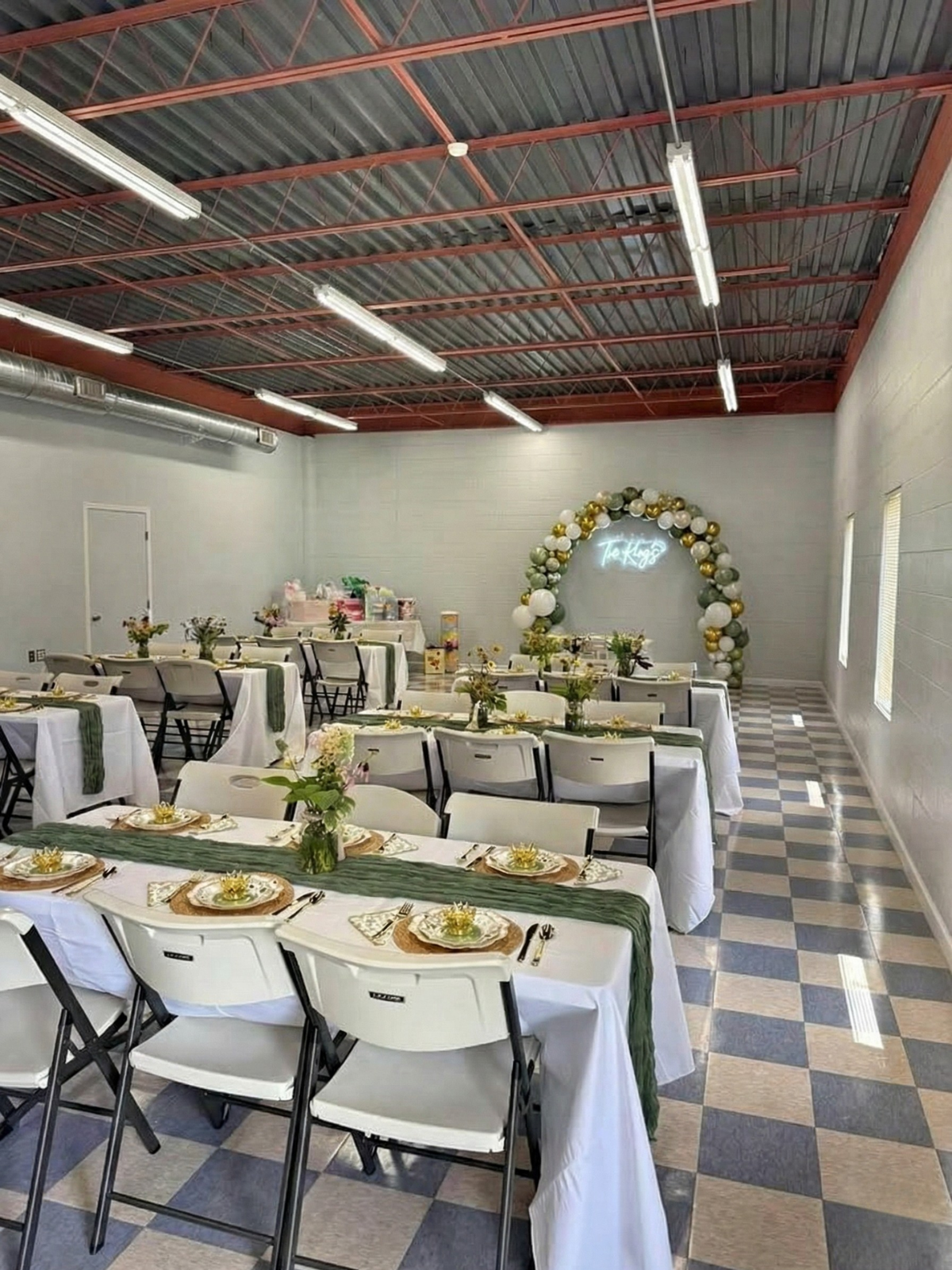 A person opening the service window of a green food truck, parked on gravel.