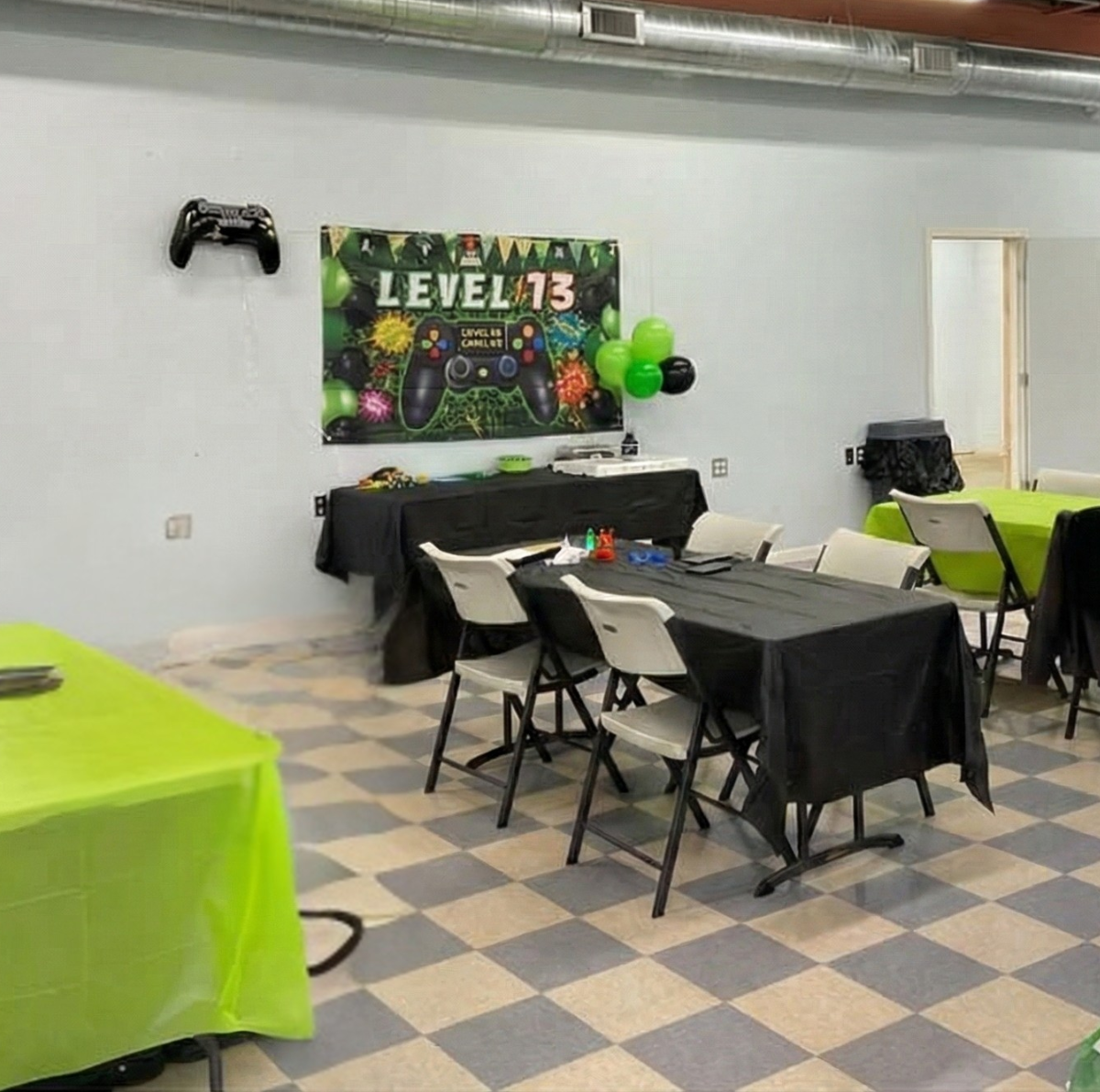 People setting up a party in a large room, with tables, decorations, and a gaming theme.