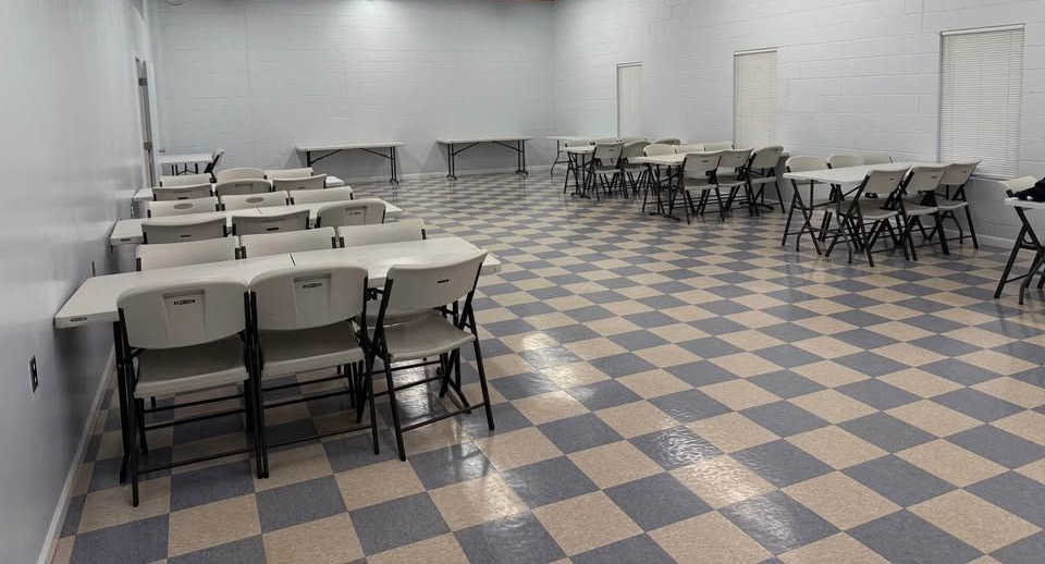 Cake with lit and blown-out candles; woman smiles in the background, out of focus.