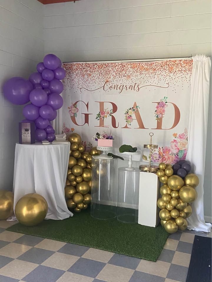 Graduation party setup with purple, gold balloons, backdrop reading