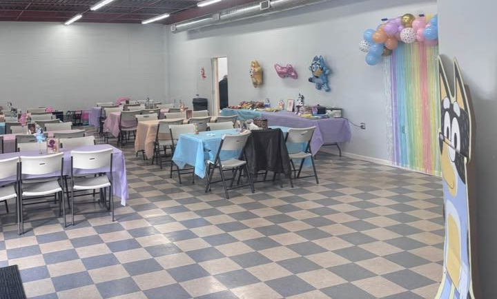 Birthday cake with lit and blown-out candles, woman smiling in background.