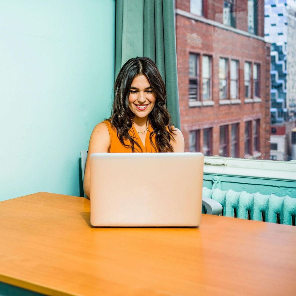 A woman is sitting at a table using a laptop computer.