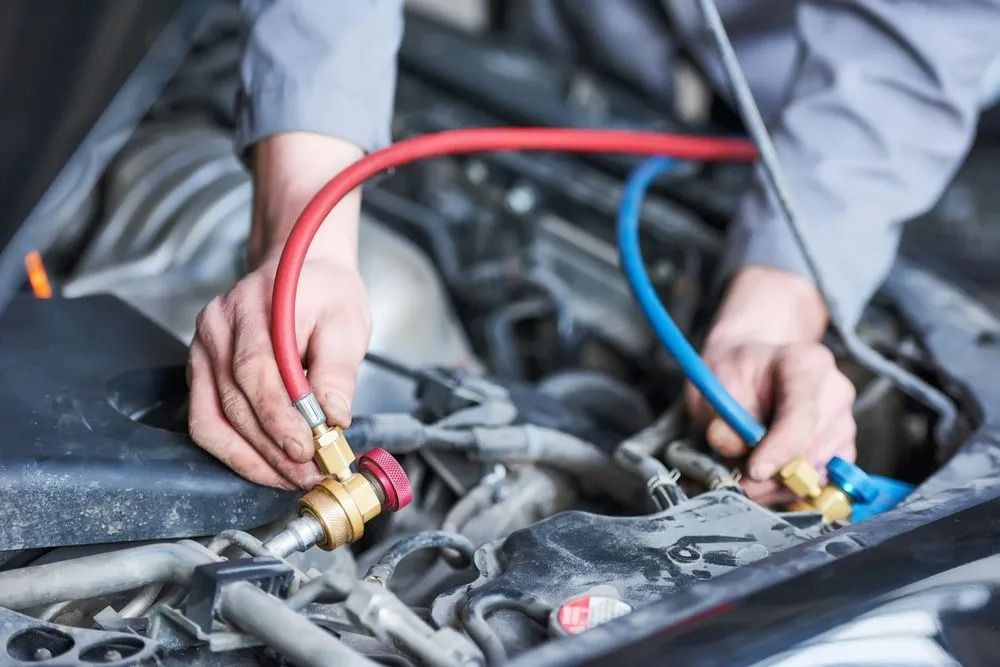 A Mechanic Connects Red and Blue Refrigerant Hoses to a Car Engine — B & W Commercials In Kempsey, NSW