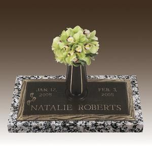 a gravestone with a vase of flowers on top of it .