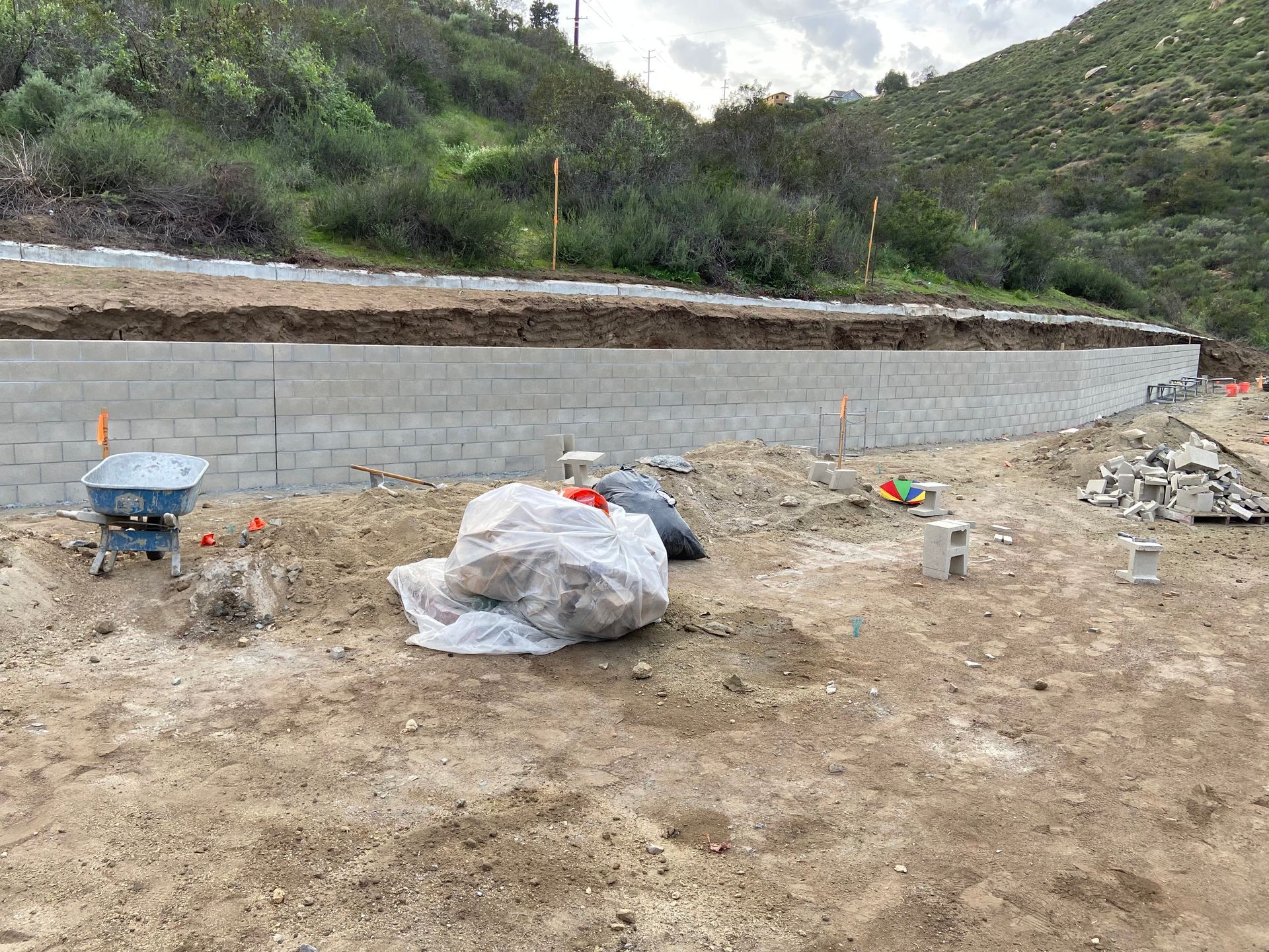 Construction site, dirt piles, and equipment in front of a mountain.