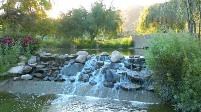 a waterfall is surrounded by rocks and trees in a park .