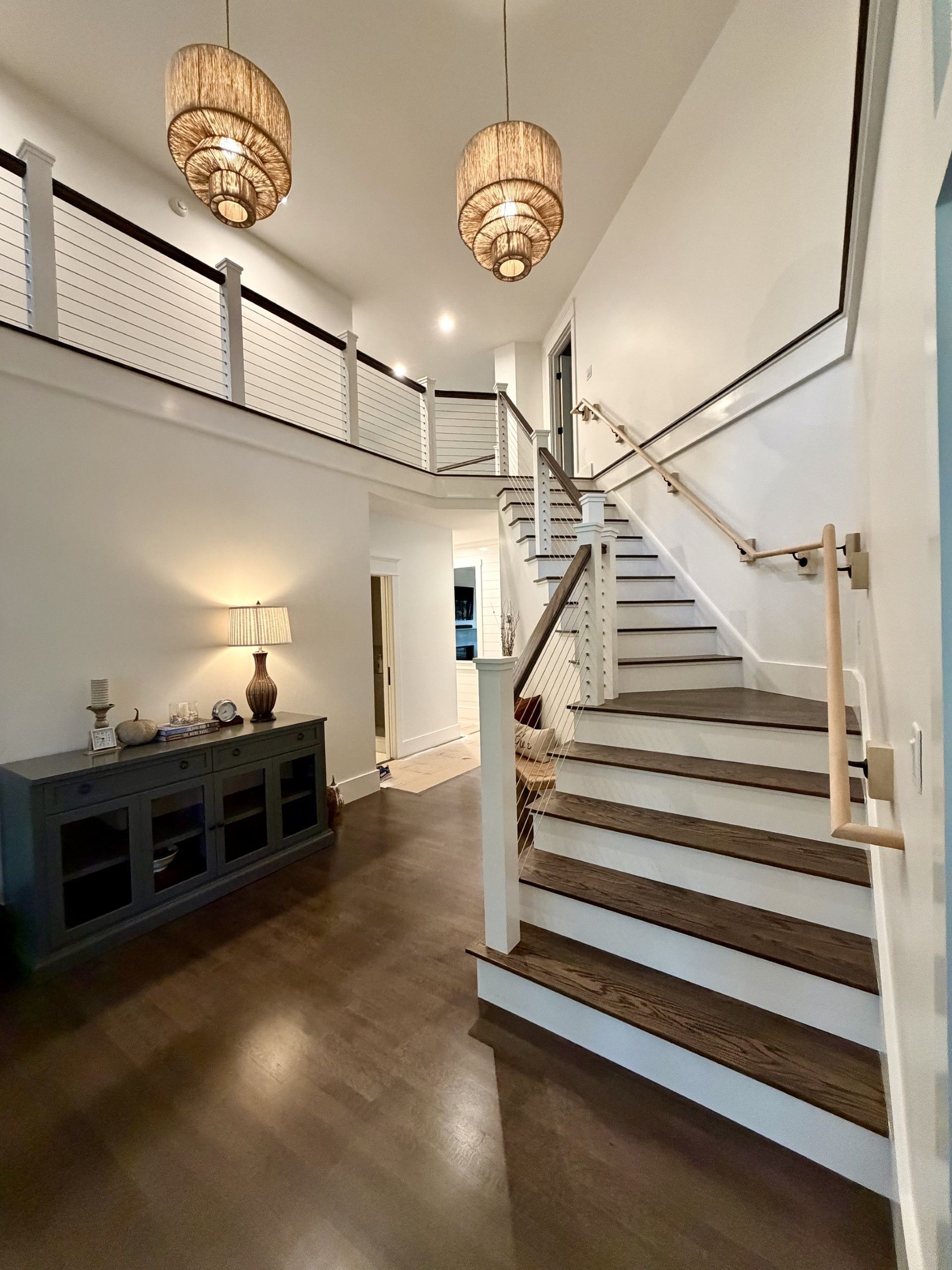Kitchen with gray island, white cabinets, wood beams, and stools. Green apples in a basket.
