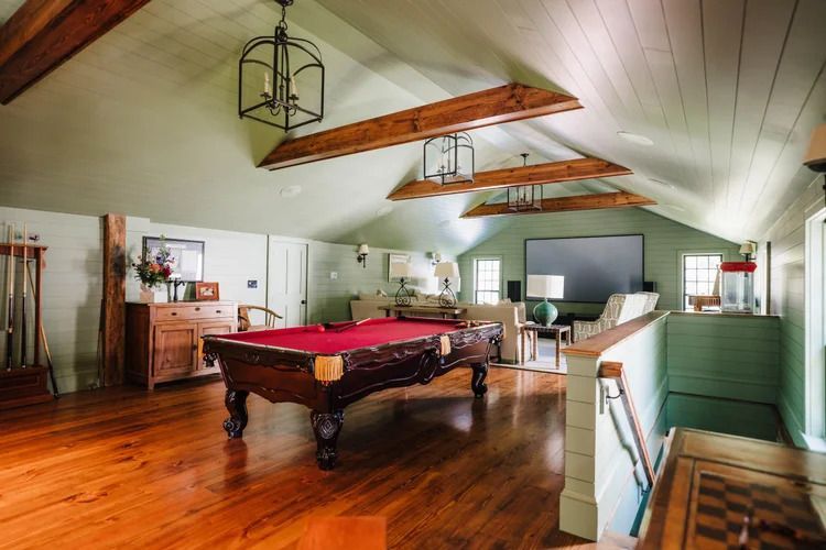 Pool table in a room with wood floors, exposed beams, and a large screen.