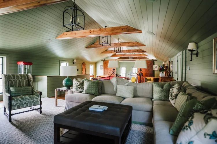 Living room with a sectional sofa, ottoman, and green paneled ceiling.