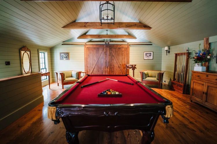 Pool table in a rustic room with wooden beams and a red felt table.