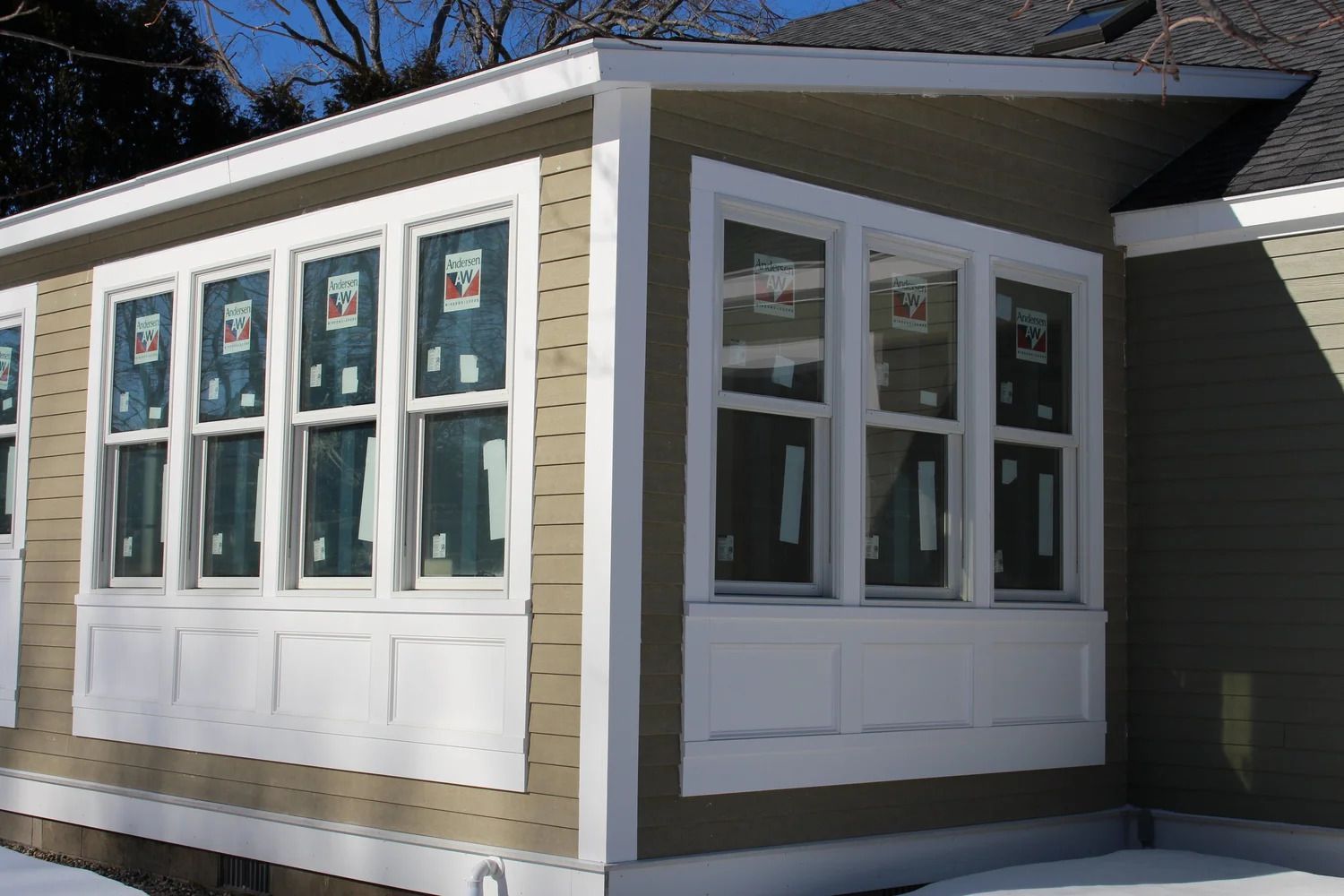 Exterior of a building with multiple windows. Beige siding with white trim.