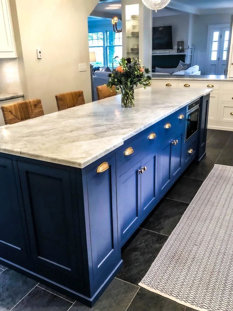 Navy blue kitchen island with marble countertop, gold hardware, and a vase of flowers.