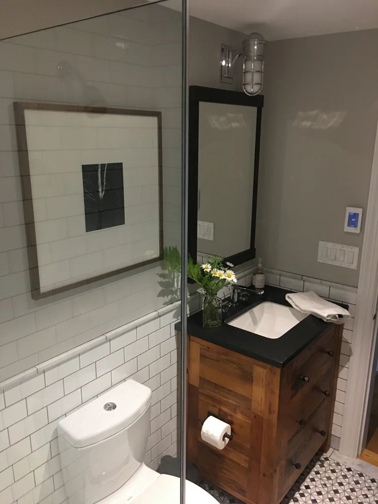 Bathroom with a white toilet, wooden vanity, black countertop, and a framed art piece.