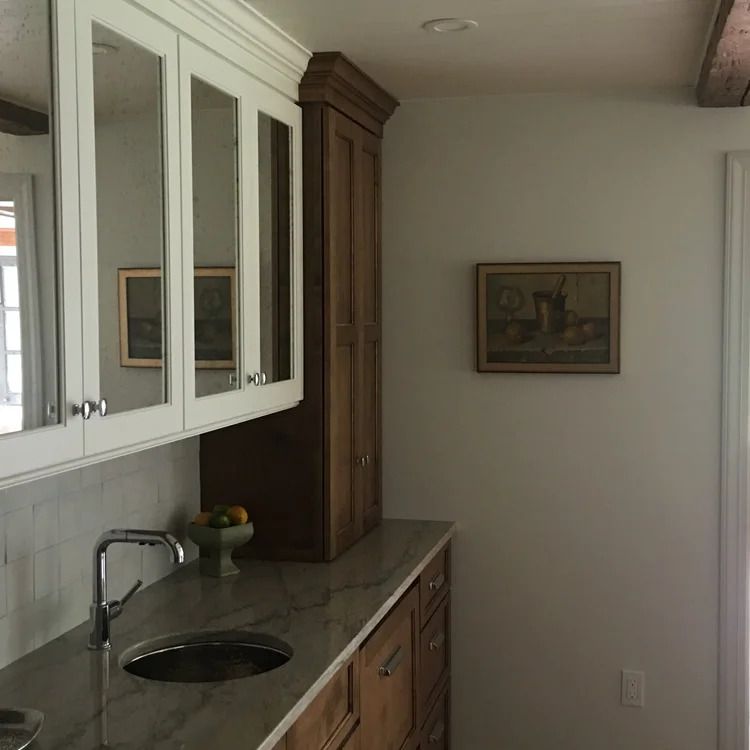 Kitchen with white and brown cabinets, marble countertop, and a small painting on the wall.