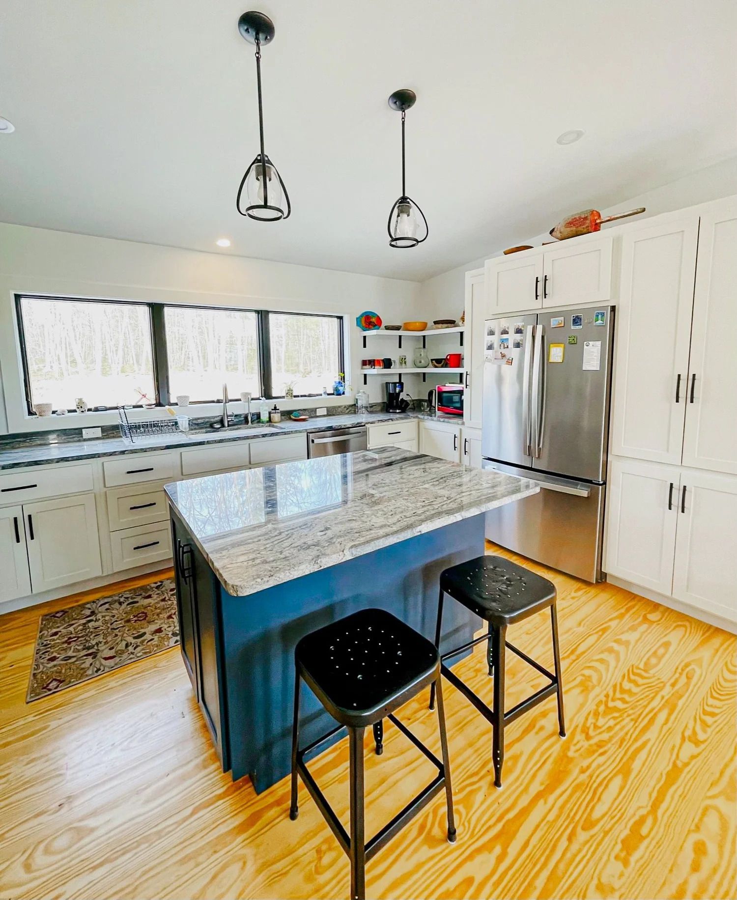 Bright kitchen with blue island, granite countertop, stainless steel appliances, and white cabinets.