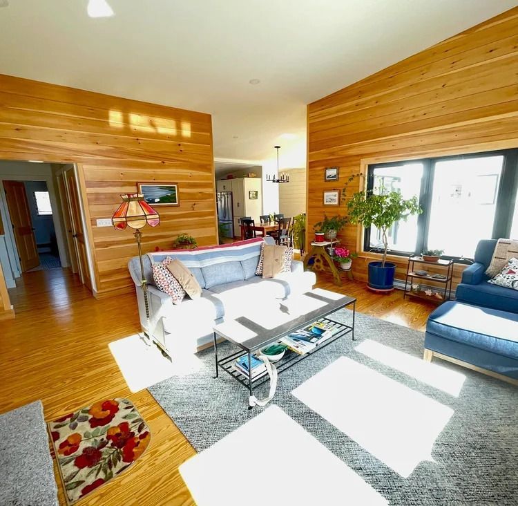 Living room with wood paneling, blue furniture, rug, and sunlight.