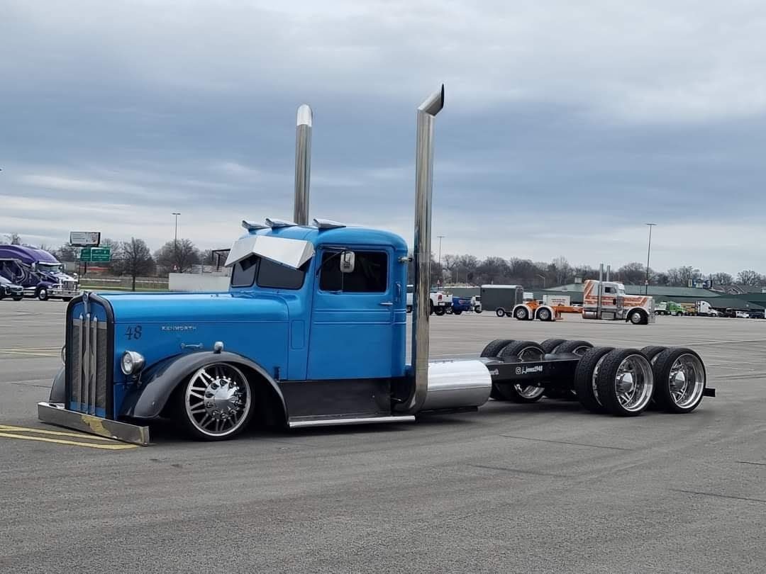 A blue semi truck is parked in a parking lot.