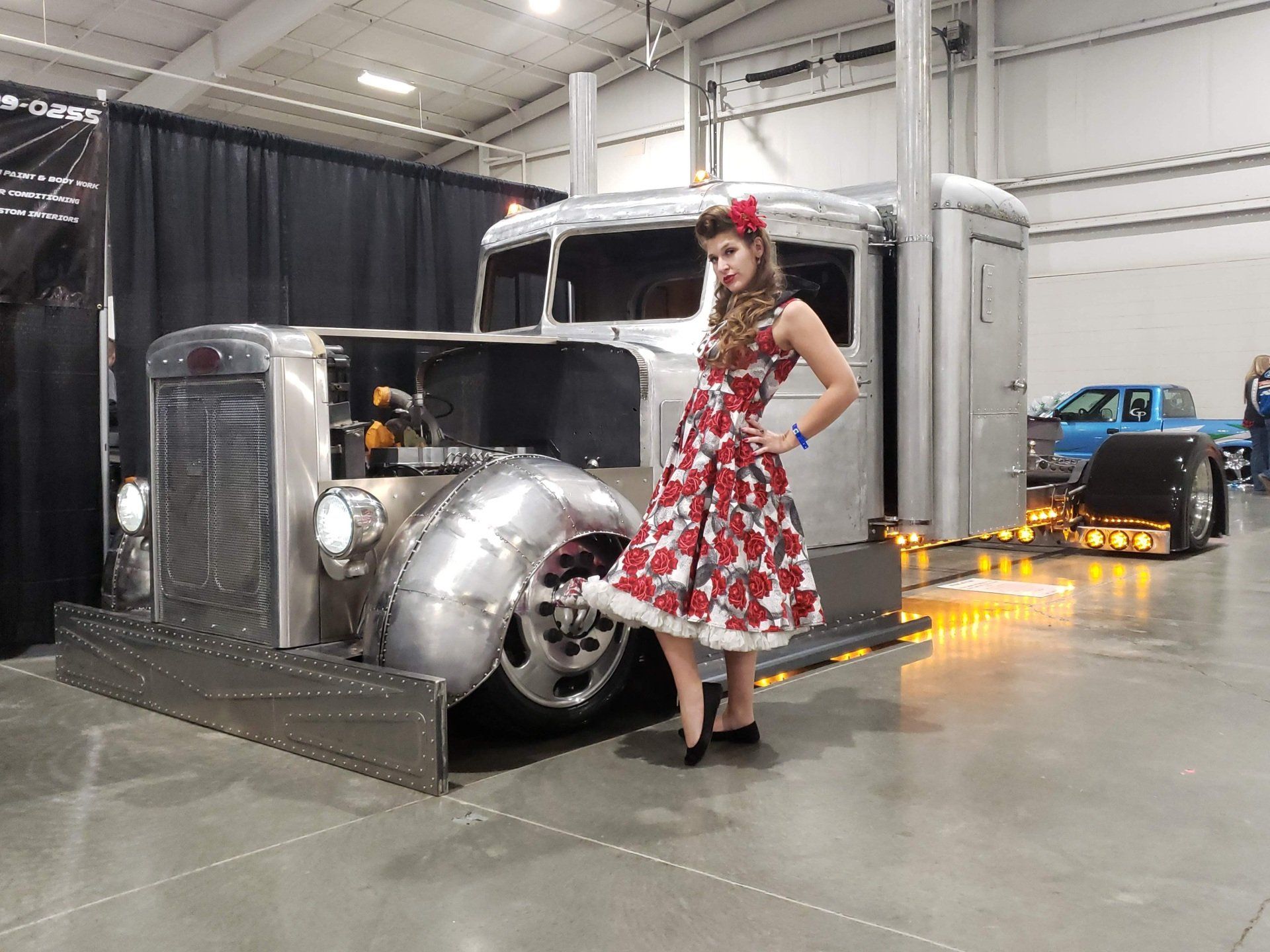 A woman in a red dress is standing next to an old truck.