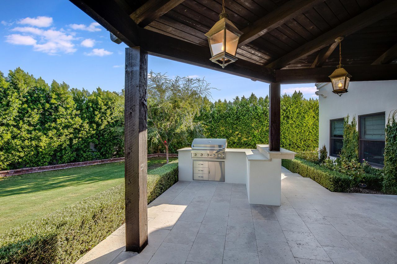 A patio with a grill and a lantern hanging from the ceiling