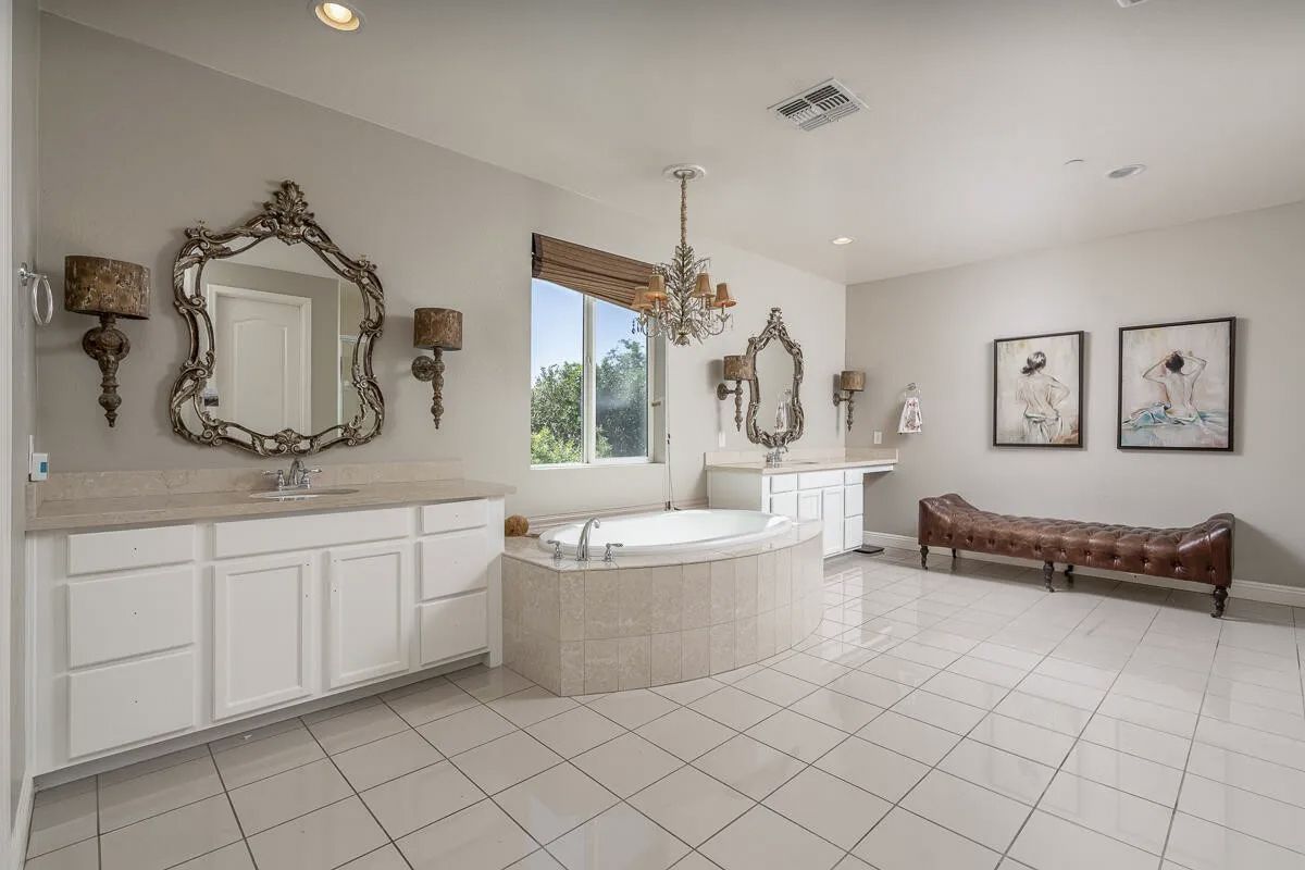 A bathroom with a tub , sink , mirrors and benches.