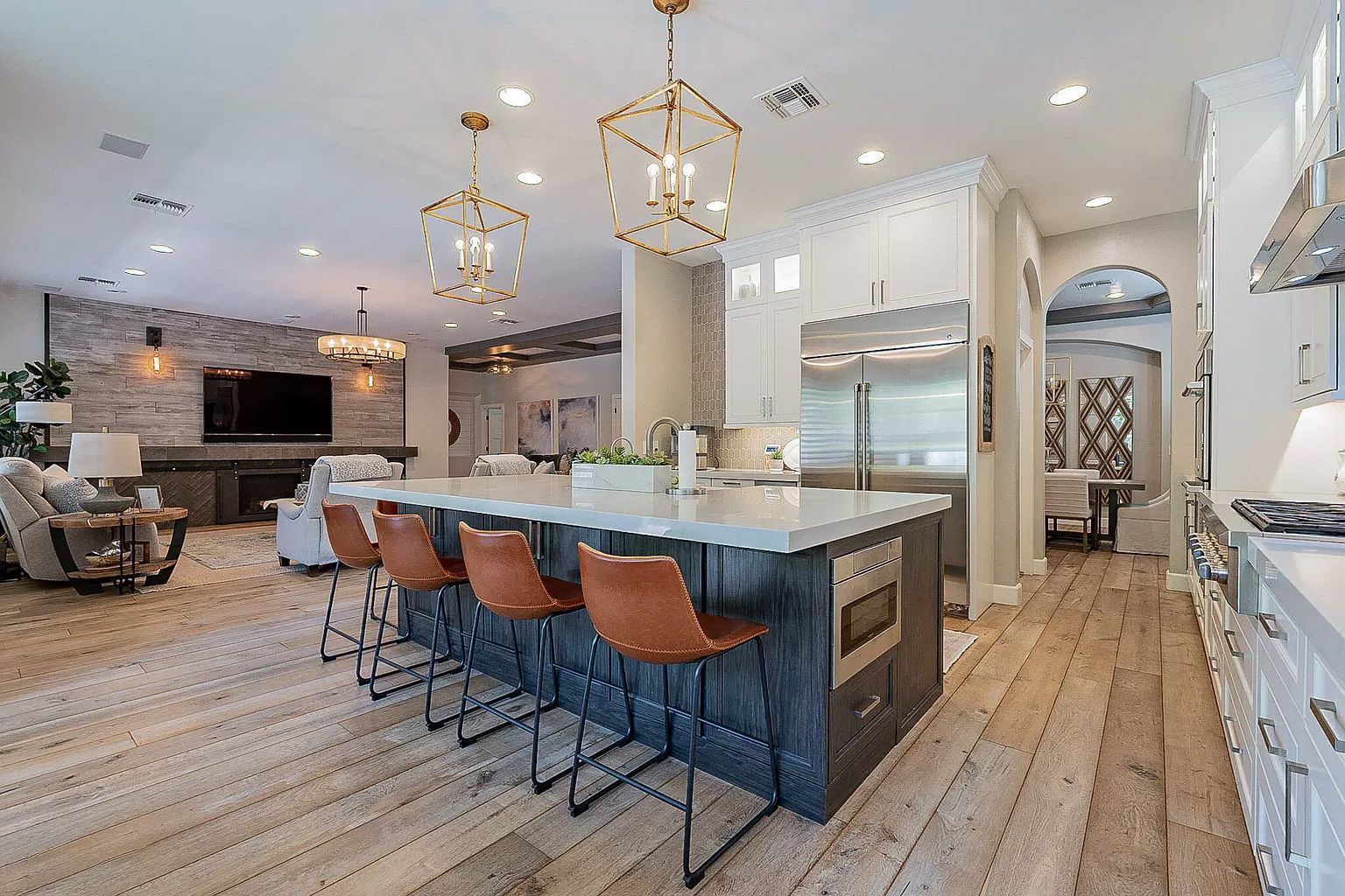 A kitchen with a large island and stools in a large house.