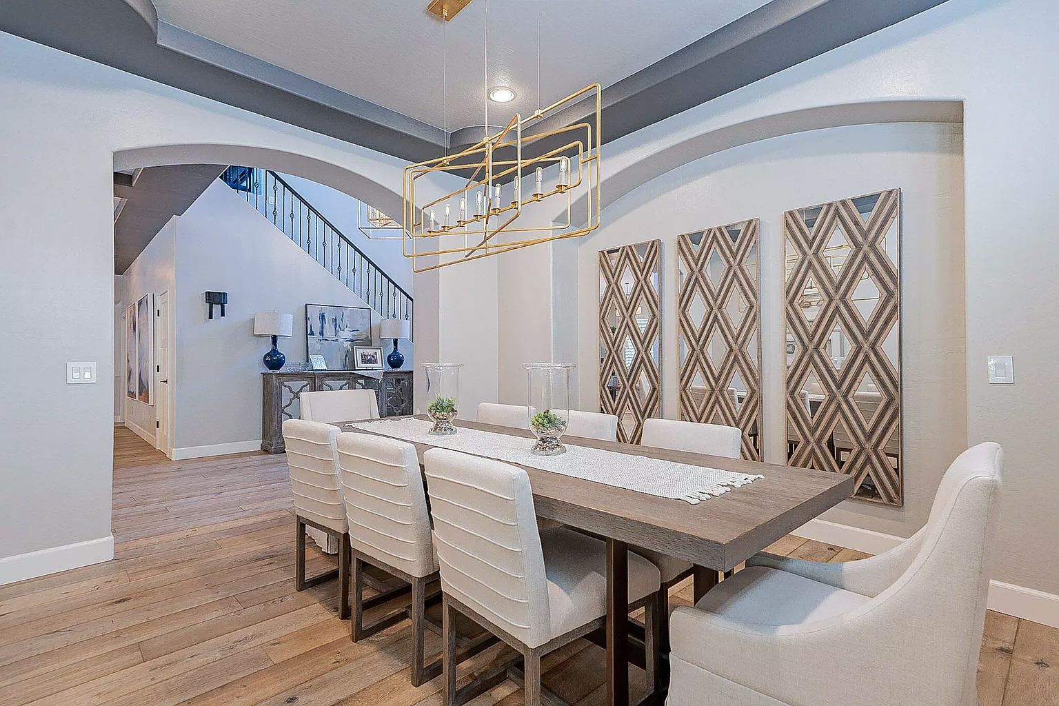A dining room with a long table and chairs and a chandelier hanging from the ceiling.