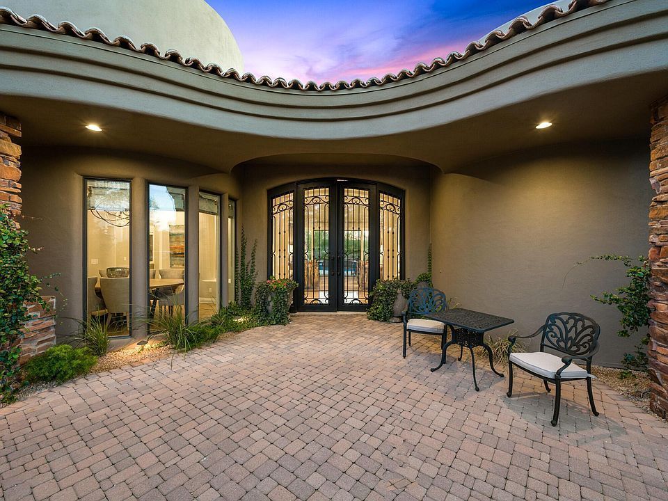 A patio with a table and chairs in front of a house.