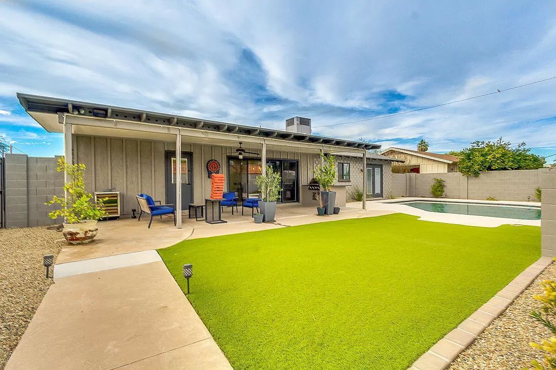 The backyard of a house with a large lawn and a swimming pool.