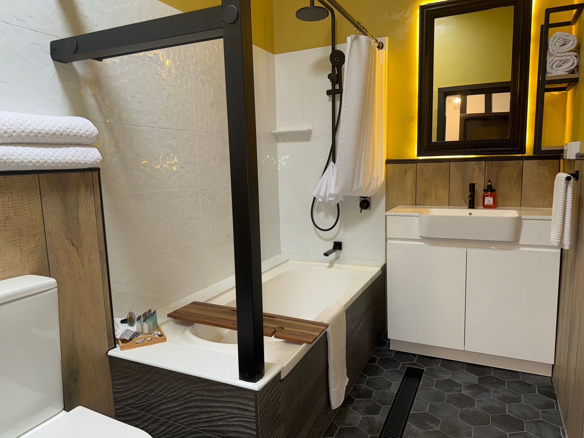 A bathroom with a bathtub , sink , toilet and mirror.