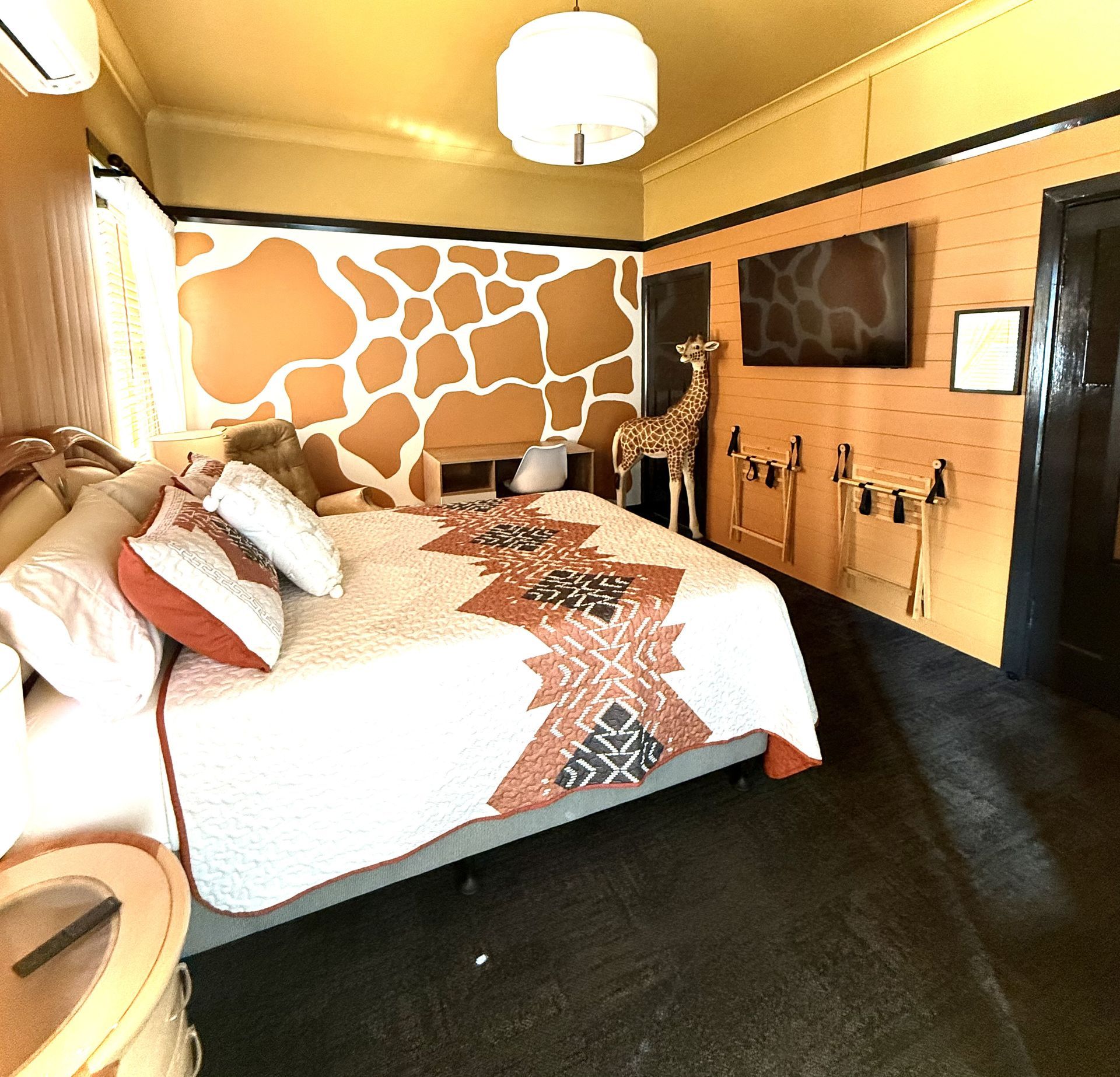 A bedroom with a large bed and a giraffe on the wall