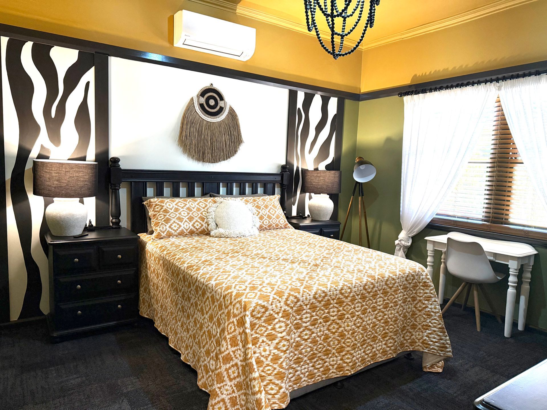 A bedroom with a bed , nightstand , desk and window.