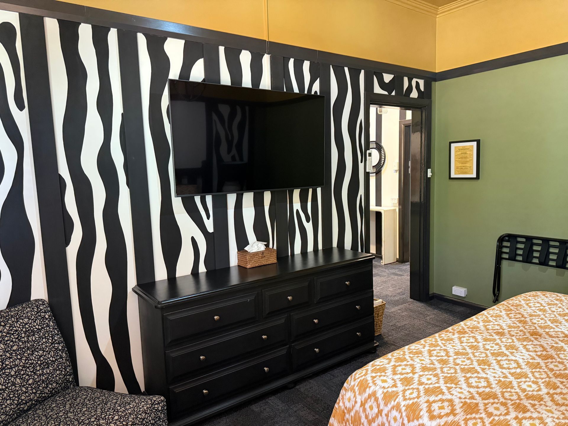 A hotel room with a zebra print wall and a flat screen tv.