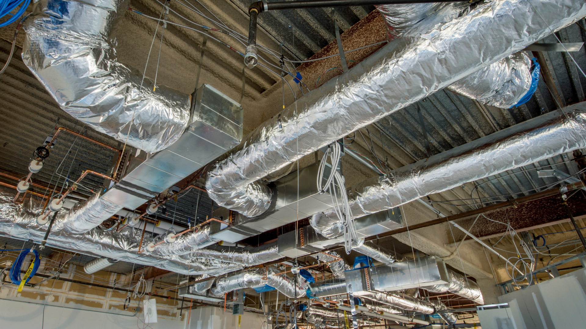 Ceiling with exposed HVAC ducts wrapped in silver insulation.