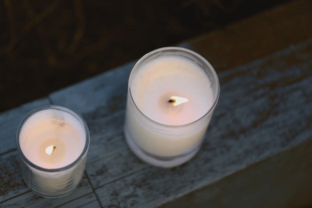 Two lit candles in glass holders on rustic surface, symbolizing remembrance, cremation services Fult