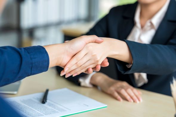 A man in a suit and tie with two other people shaking their hands