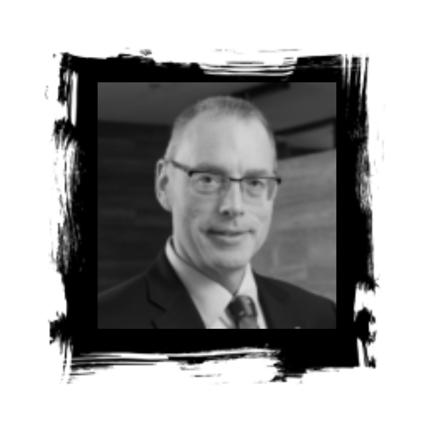 Man wearing glasses and a suit, framed with a black, textured border.