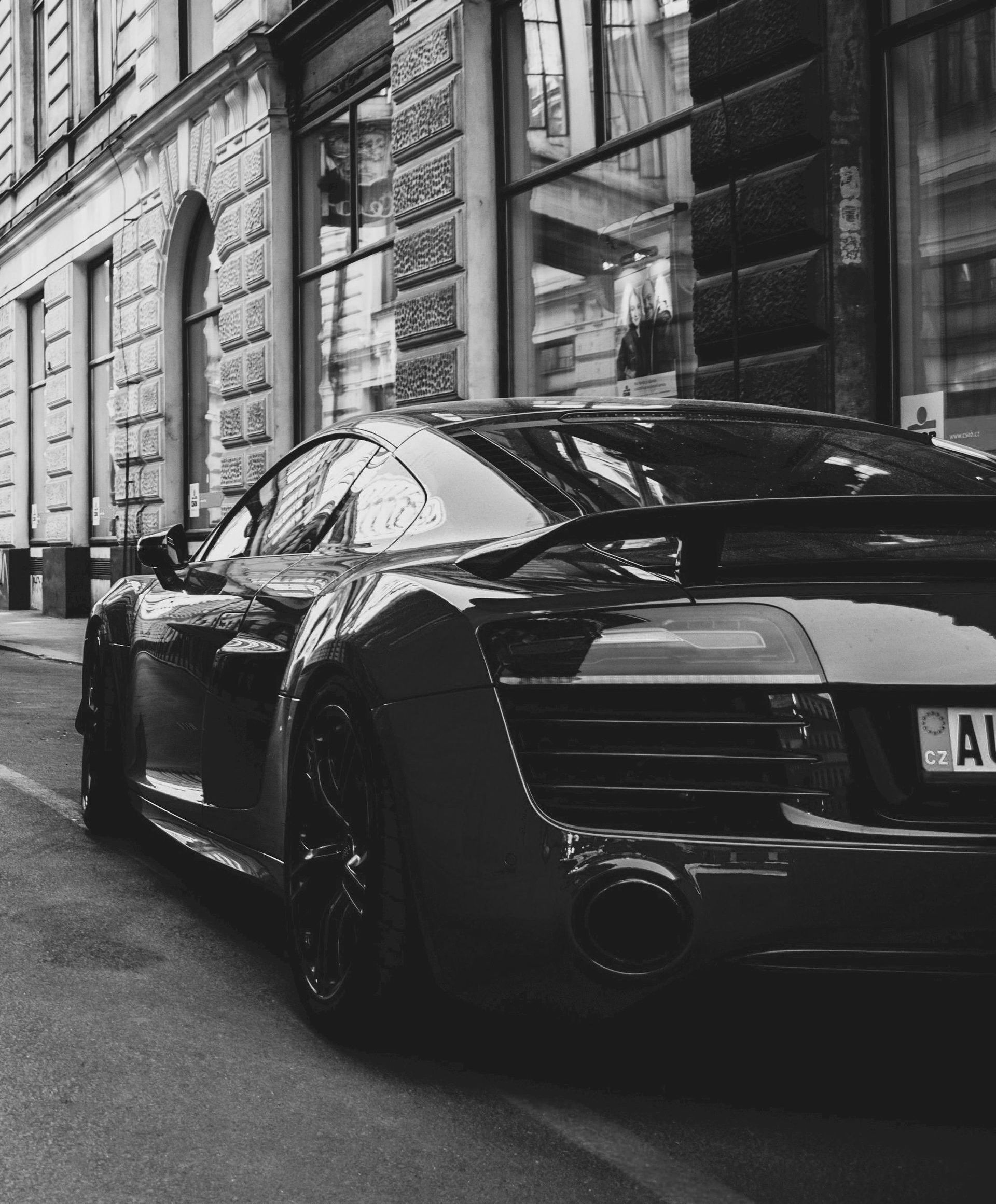 Black sports car parked on a city street next to a building.