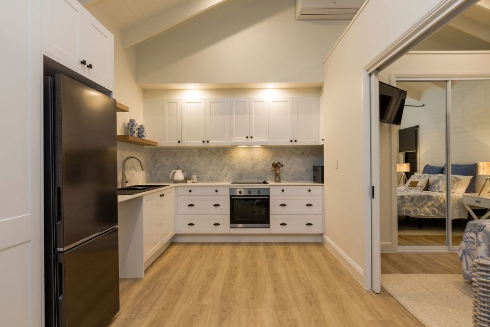 A Kitchen with White Cabinets and A Black Refrigerator — Rodney Lees Cabinetmaking In Monaltrie, NSW
