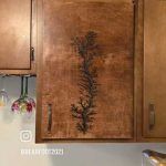 Wood cabinet with a burned-in fractal-like design; a wine glass holder is visible to the left.