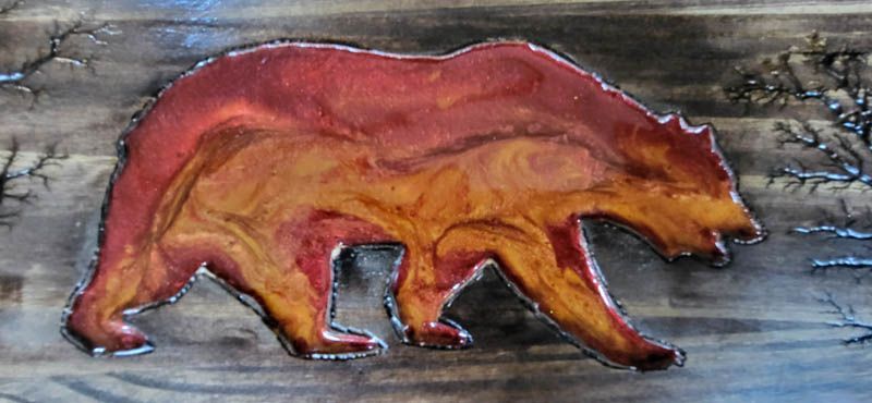 A colorful bear on wood, with fiery colors.