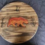Wooden serving tray with a carved and painted bear and trees.