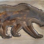 Raised relief of a bear and cub, in shades of brown, on wood.