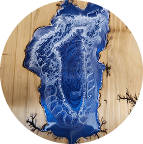 Round wooden art with blue resin river detail. Wood has lightning patterns; resin is swirled with white.