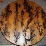 Wood plaque with intricate, dark fractal burn patterns resembling trees.