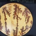 Oval wooden board with intricate fractal-like patterns burned into the wood, in tones of brown and tan.
