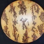 Wooden circle with scorched Lichtenberg figure designs.