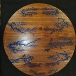 Wooden round table with blue fractal-like patterns.