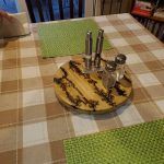 A wooden salt and pepper holder on a table with place mats.